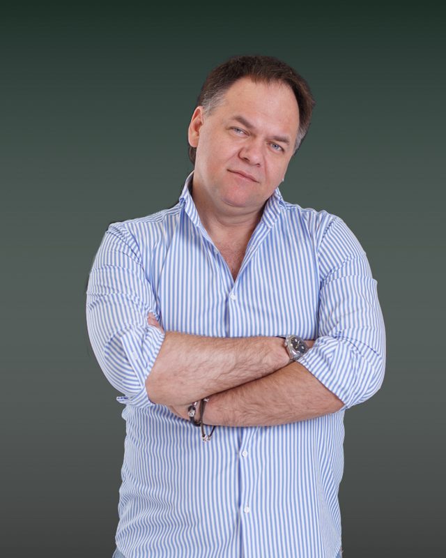 Александр Копытько со скрещёнными руками на тёмном фоне, погрудный кадр