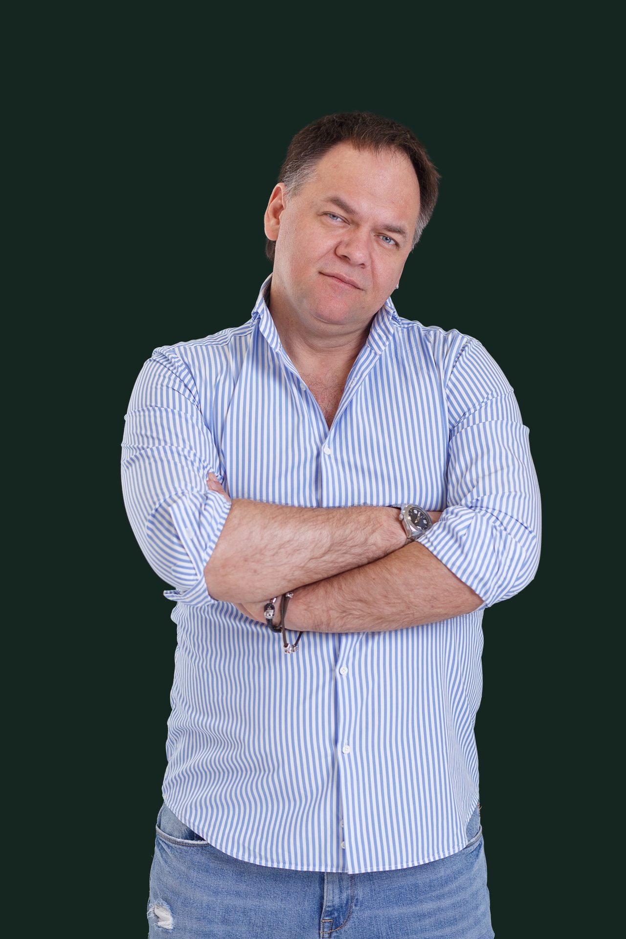 Александр Копытько стоит со скрещёнными руками, светлая рубашка в полоску, кадр в рост